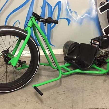 Drift trike with wide tires and black accents, parked on a street.